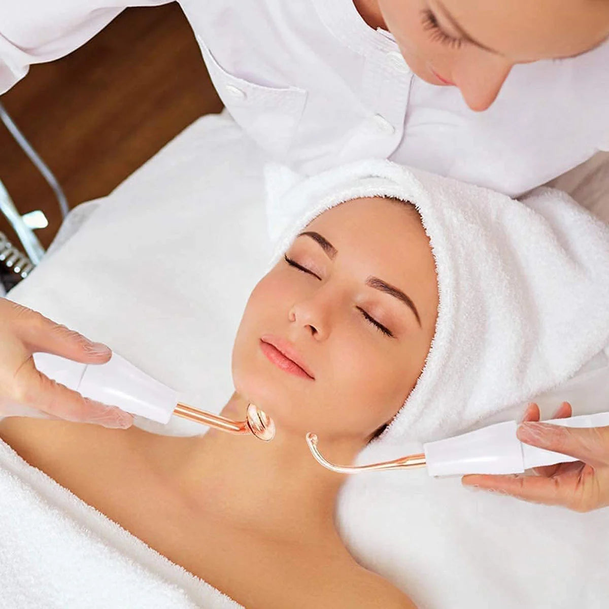 Mulher relaxada em spa recebendo tratamento OMSBIKIN com ferramentas faciais para cuidados com a pele e eletrodos dourados