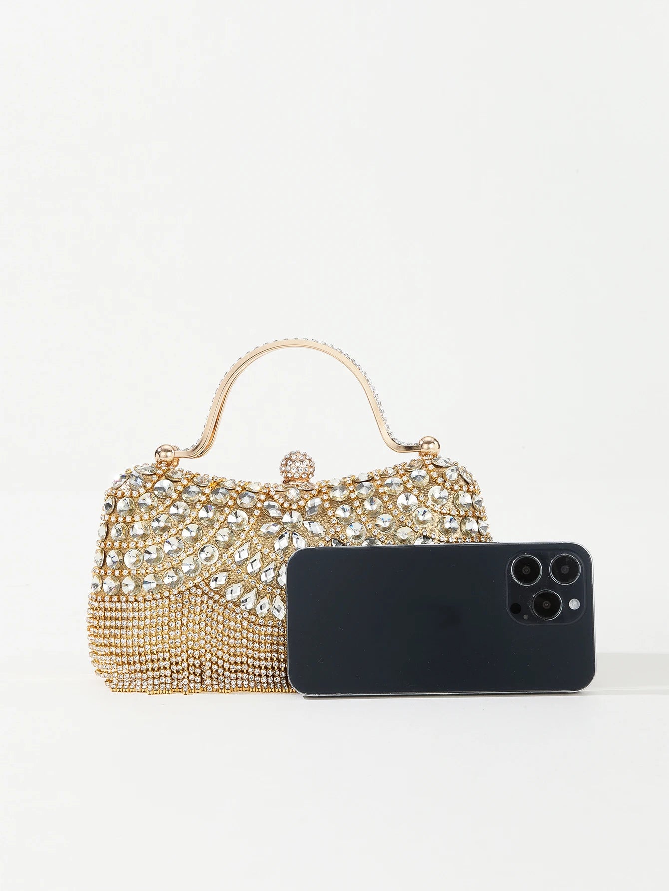 Bolsa festa com diamantes dourada com detalhes brilhantes ao lado de um celular