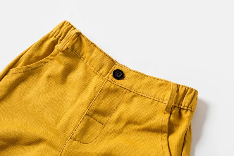 Detalhe da calça mostarda do conjunto YSOYOK, parte de roupa menino com gravata borboleta amarela, cós com botão