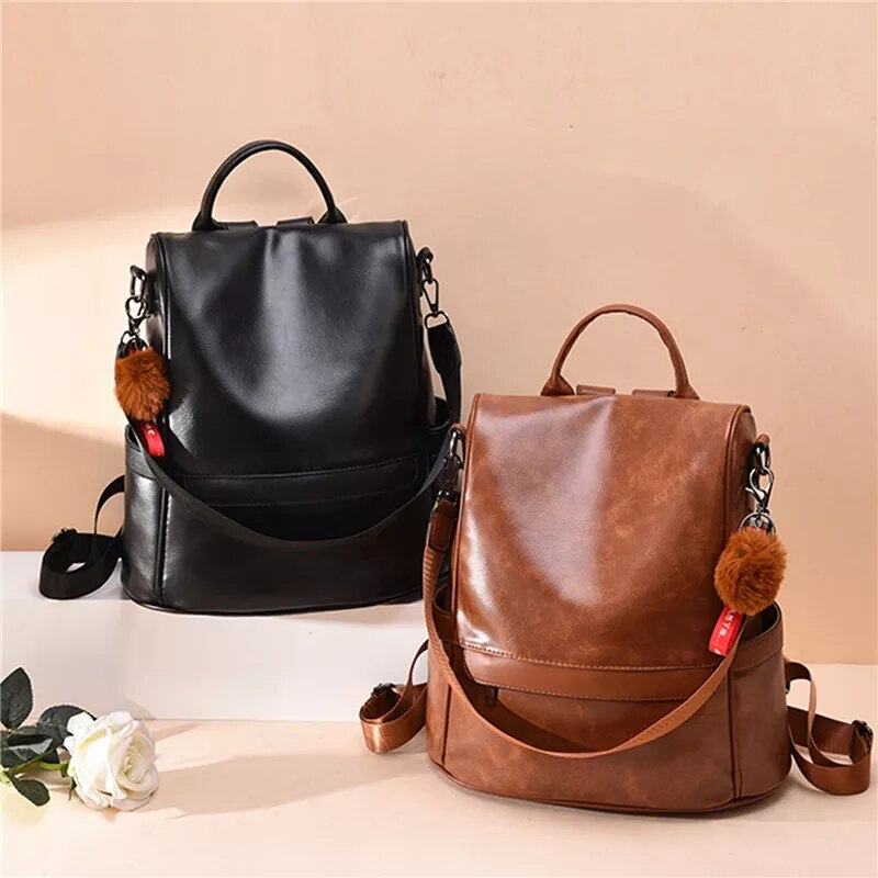 Mochila feminina de couro PU em preto e marrom com detalhe em pompom e alça ajustável