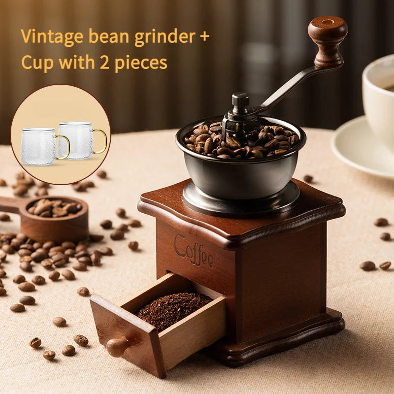 Moedor de café com cabo de madeira vintage, acompanhado de canecas em uma mesa com grãos de café