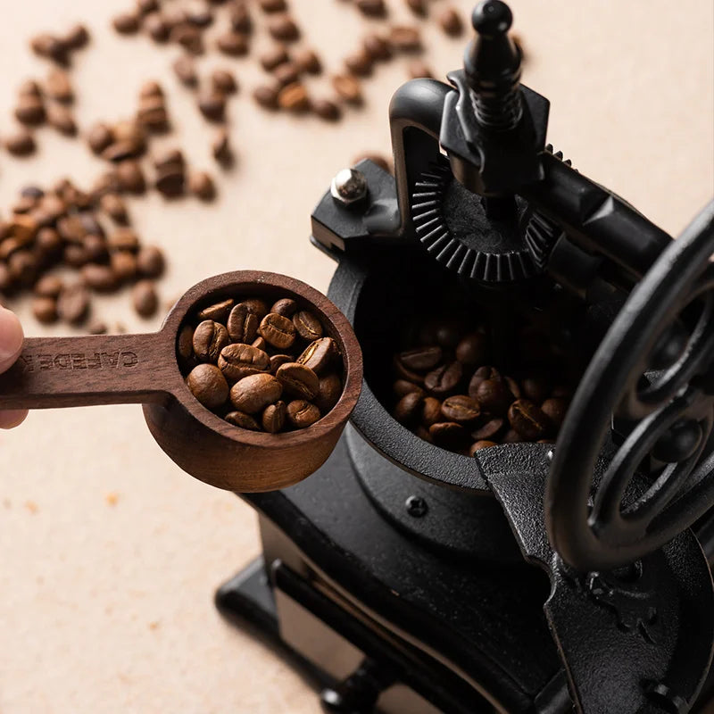 Moedor de café manual retrô GIANXI com grãos de café prontos para moagem em uma colher de madeira