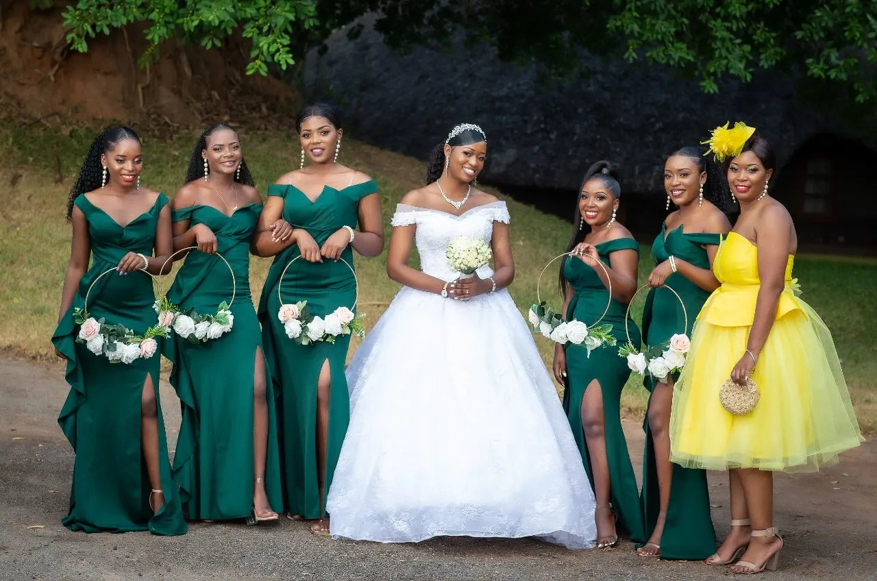 Grupo de damas de honra com vestidos verdes, incluindo um vestido de baile sereia com fenda, e a noiva em branco