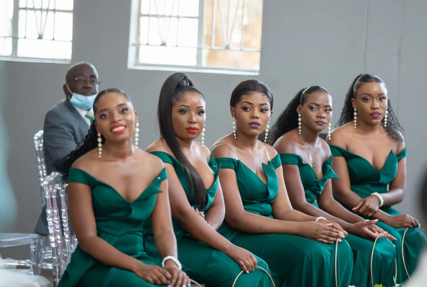 Grupo de mulheres vestindo vestido de baile sereia com fenda em tom verde, sentadas em um ambiente elegante