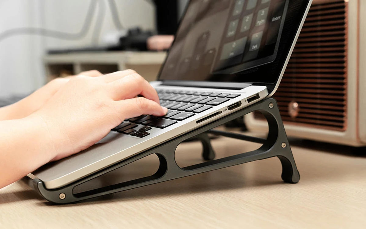 Suporte vertical para notebook ORICO em uso, elevando um MacBook para melhor ergonomia