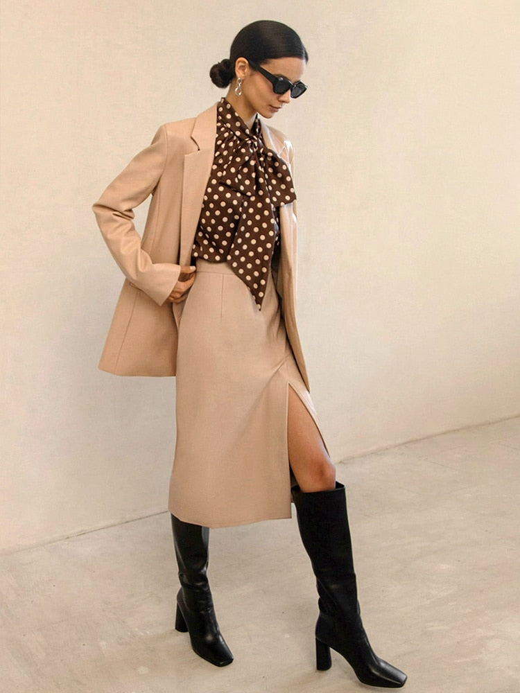 Saia de couro preta feminina combinada com blazer e camisa de bolinhas para um look elegante