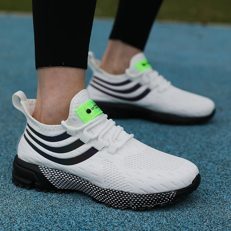 Tênis Esportivo Malha Respirável com Almofada em branco com detalhes em preto e verde, ideal para atividades físicas.