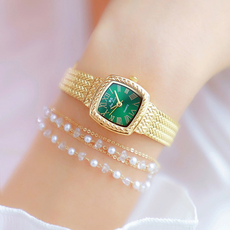 Relógio feminino dourado com mostrador verde e pulseira trançada, ideal para looks elegantes.
