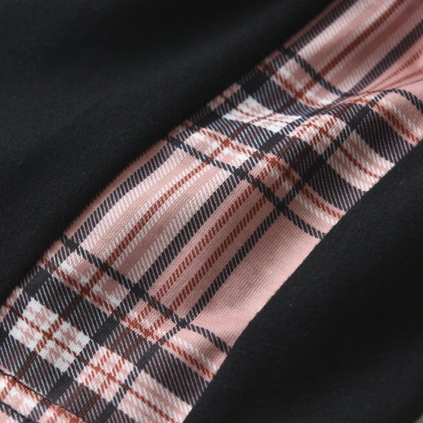 Detalhe de tecido preto com faixa xadrez rosa e preto mostrando conjunto camiseta manga curta e bermuda menino KUKITTY