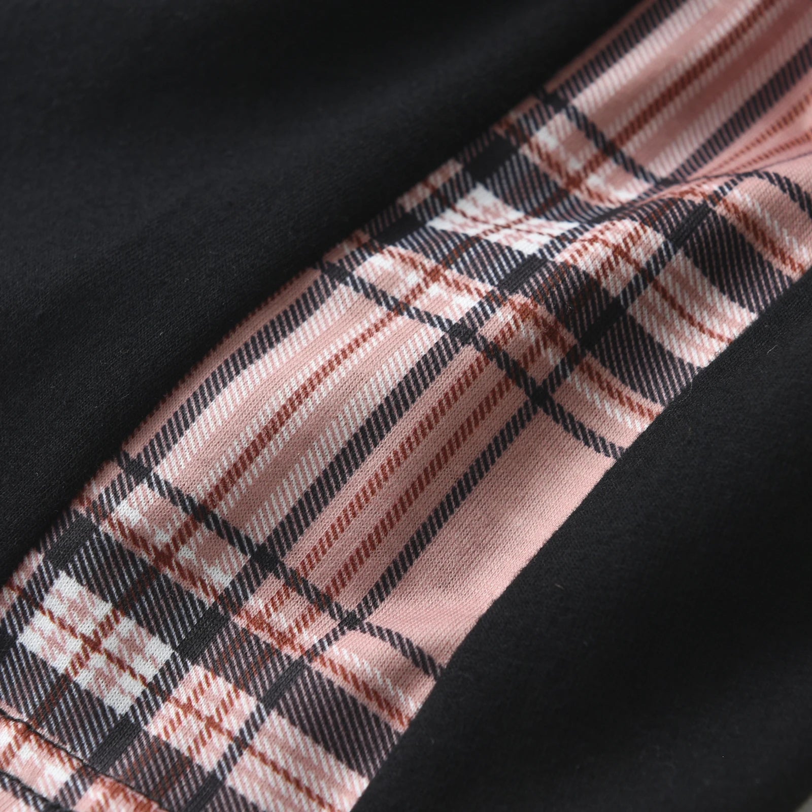 Detalhe de tecido preto com faixa xadrez rosa e preto mostrando conjunto camiseta manga curta e bermuda menino KUKITTY