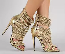 Sandálias femininas Comemore em dourado com salto alto e detalhes em corrente, ideal como sapato feminino social palco salto alto