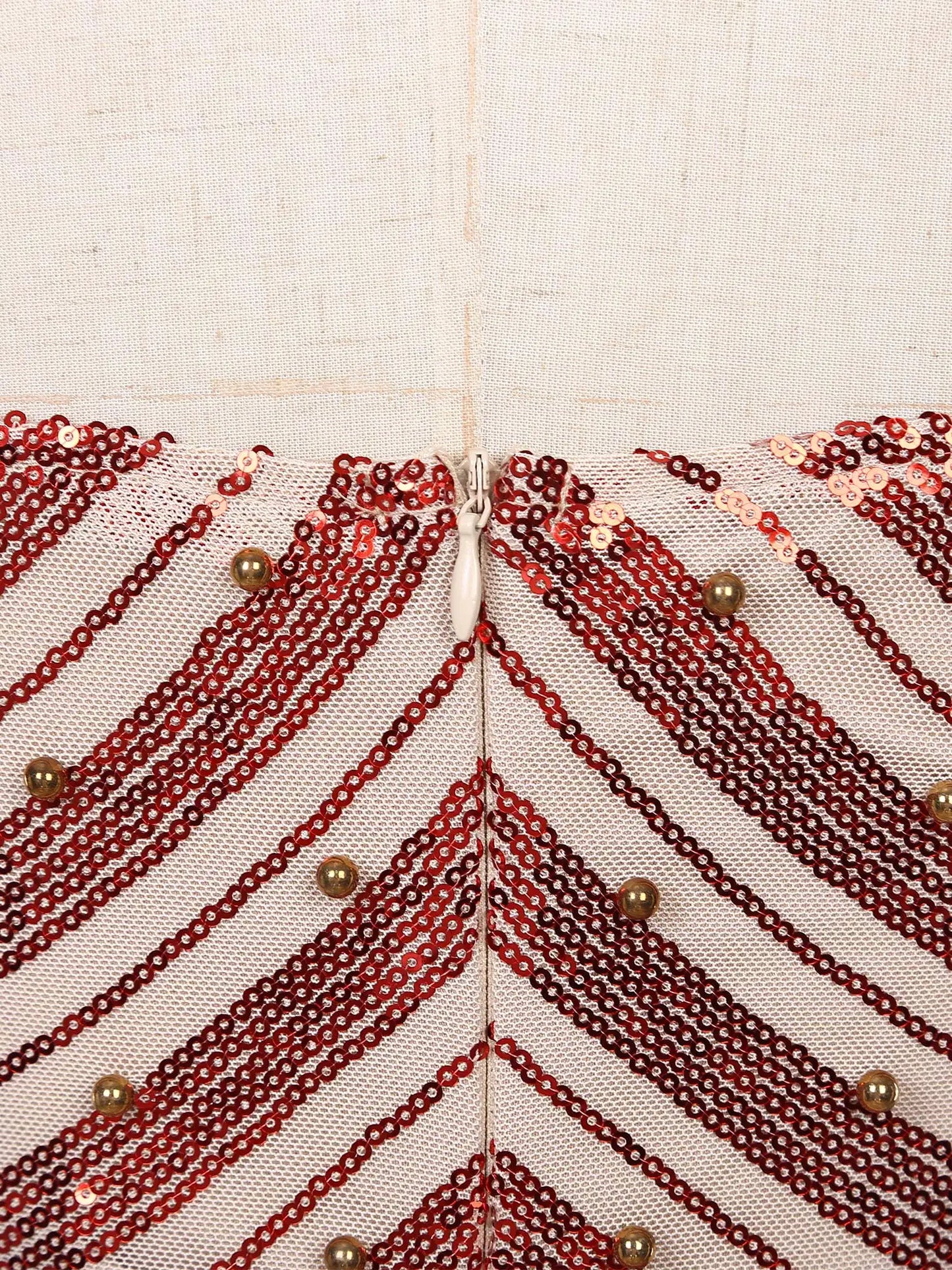 Detalhe das costuras de um mini vestido feminino com lantejoulas em padrão diagonal de cores quentes